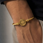 Bracelete dourado de São Bento em pulso masculino